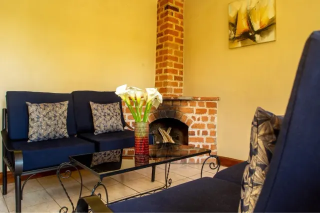 The cottage lounge at Mullers — deep blue sofas, a brick fireplace, and calla lilies on the low table